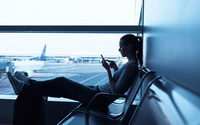 INDIA_Woman-waiting-in-airport-terminal-using-her-smartphone